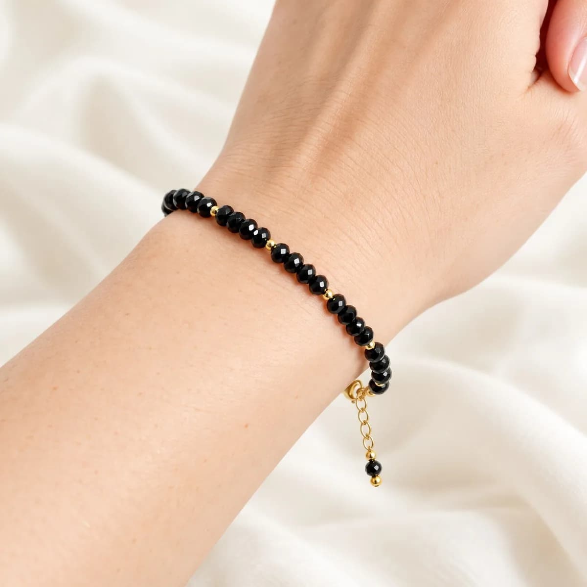 Handmade beaded bracelet with black faceted beads and gold-tone accent beads worn on a wrist